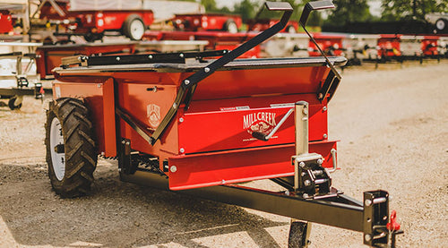 Red farm implement with 'Mill Creek' branding on a gravel surface.