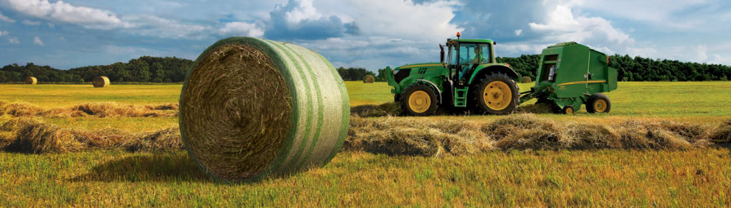 baling hay in a hay field with a round baler